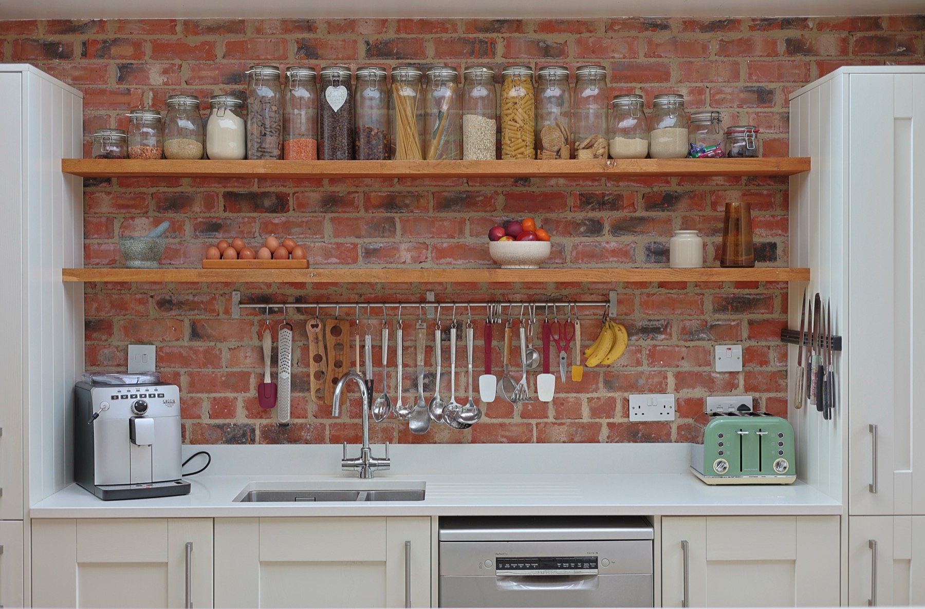 Exposed brick kitchen wall with open oak shelving