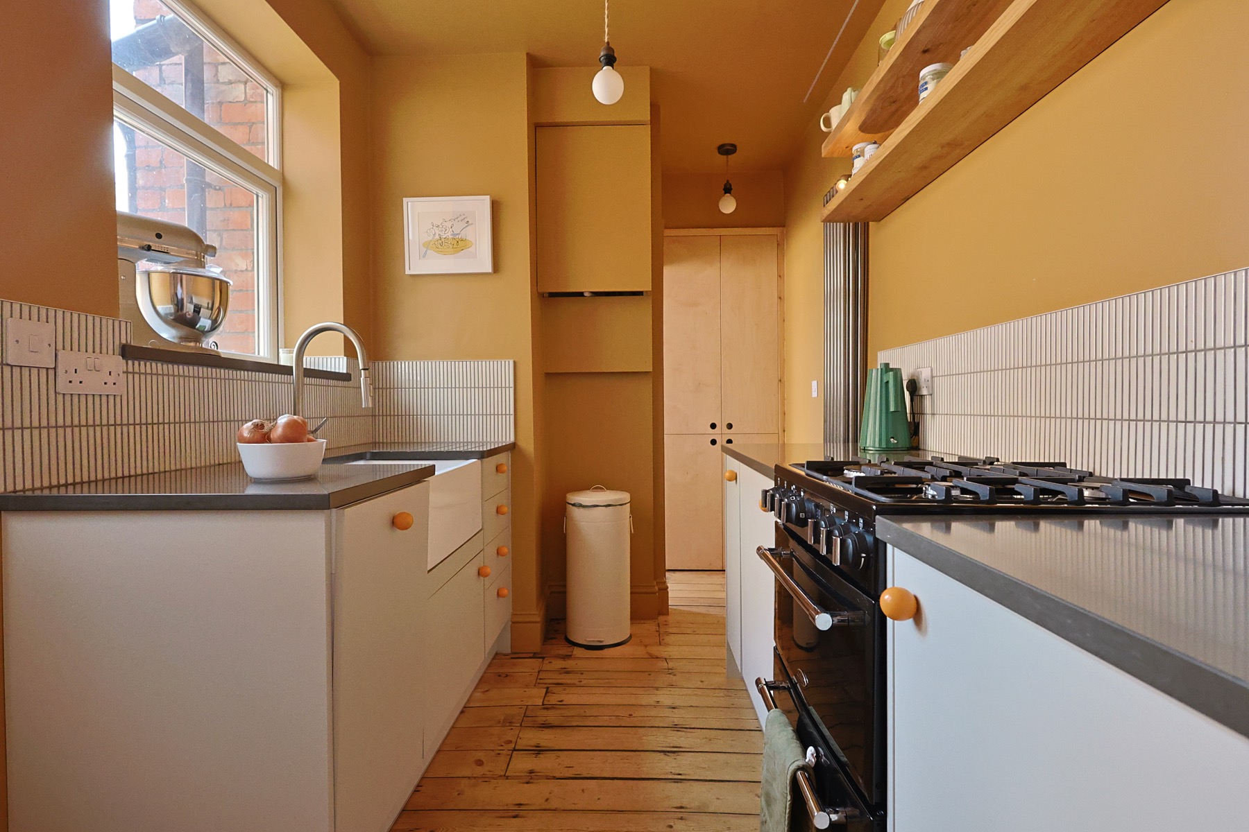 Ochre kitchen with a range cooker, open shelving and stripped floorboards