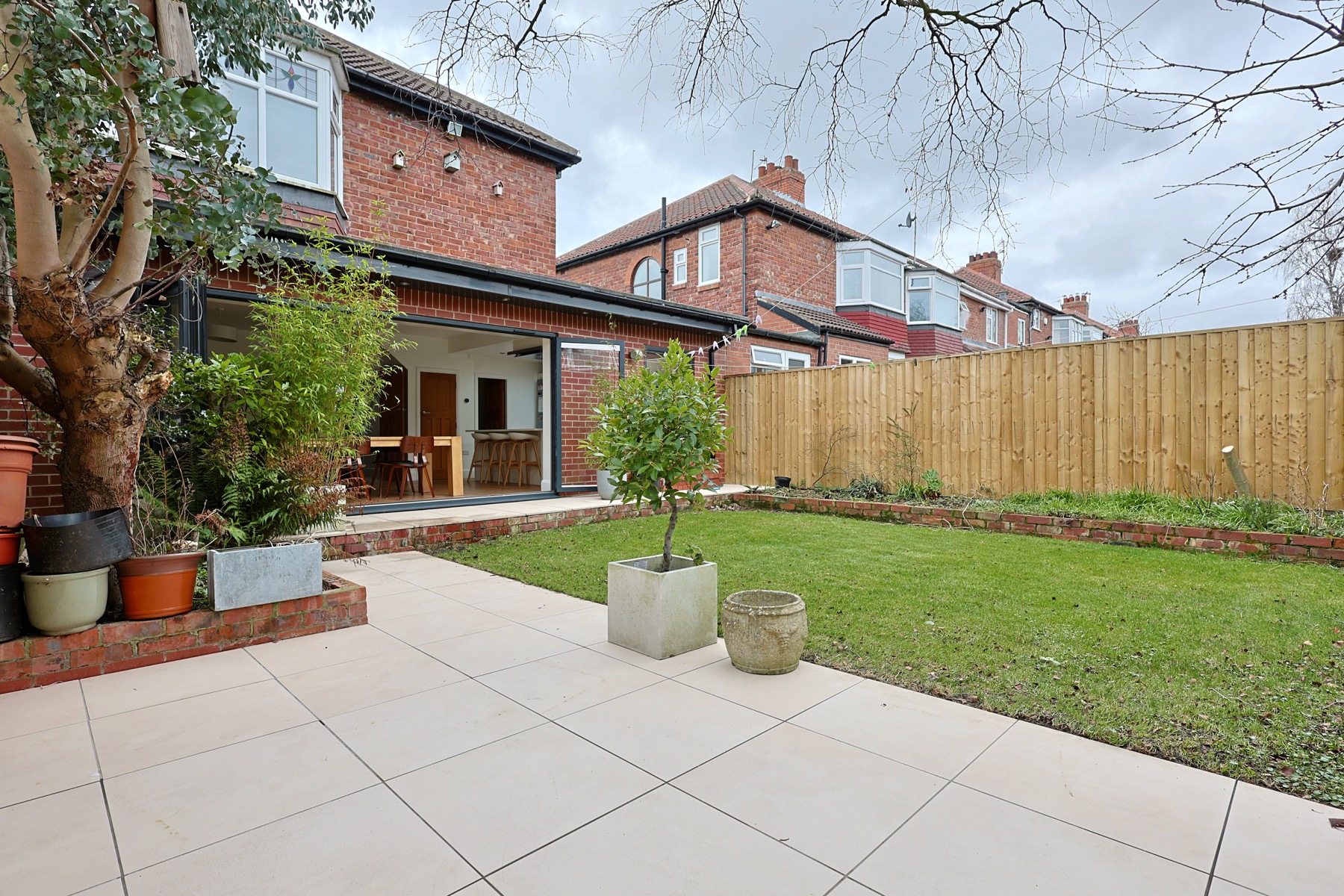 A paved terrace and lawn behind a brick semi in High Heaton, photographed by Bowson